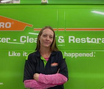 Jennifer Nix, standing in front of a green van. 