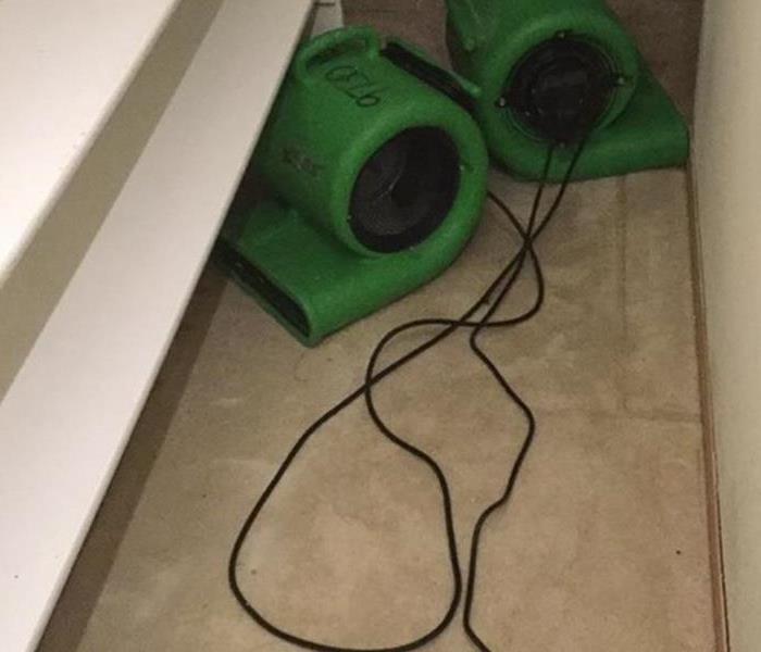 3 green air movers on a carpet in a closet