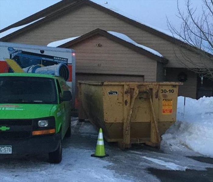dumpster and a SERVPRO van outside a residential home
